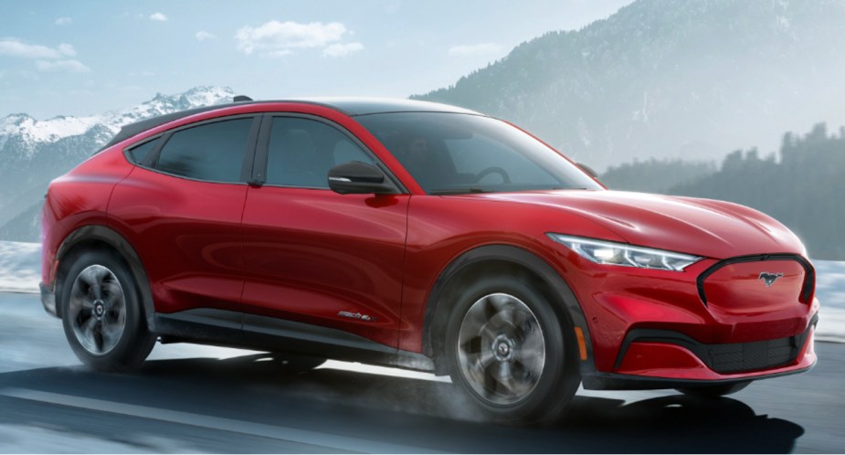 A red 2022 Ford Mustang Mach-E electric SUV is driving on the road. 