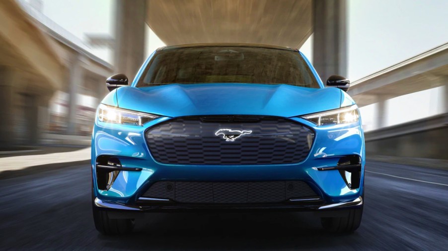 A blue 2022 Ford Mustang Mach-E electric SUV is driving on the road.