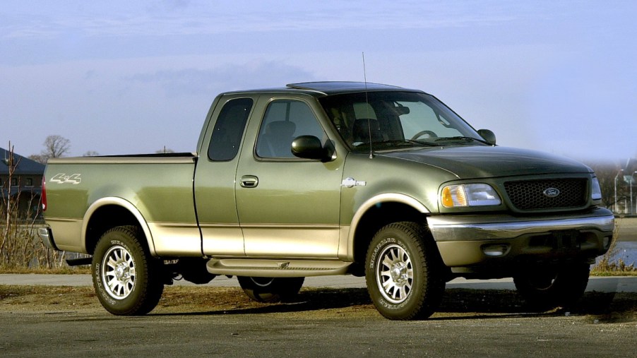 A Ford F-150 with green paint sits on a paved road.