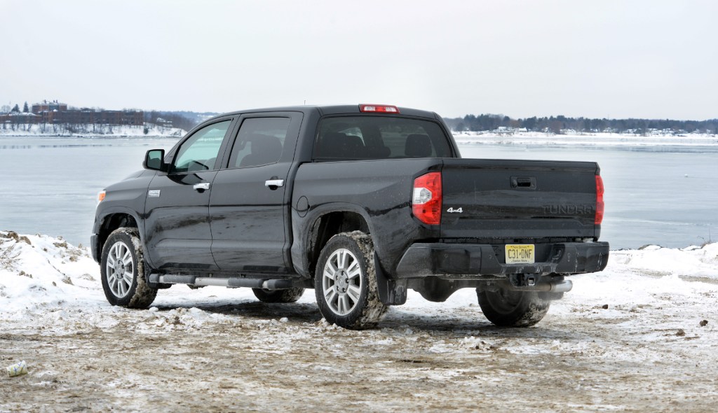 A black Toyota Tundra pickup truck sits in front of a lake. It is a used full-size truck worth buying.