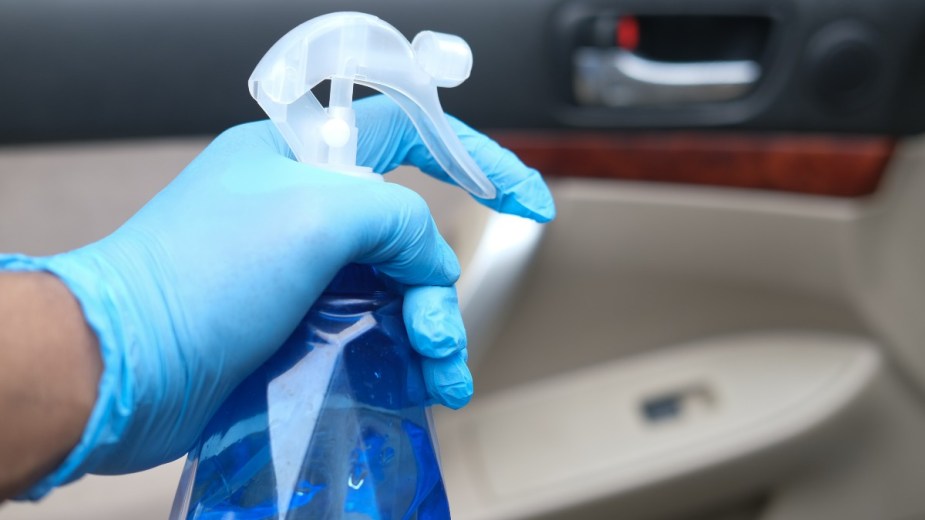 a person gets ready to detail in the interior of their car with a spray bottle