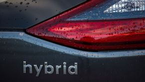 Hybrid written on the back of a gray car.