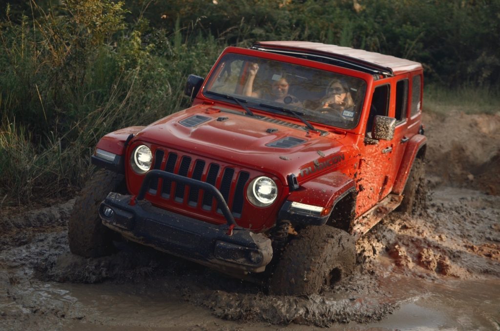 A Jeep Wrangler navigates in mud on a terrain trail.