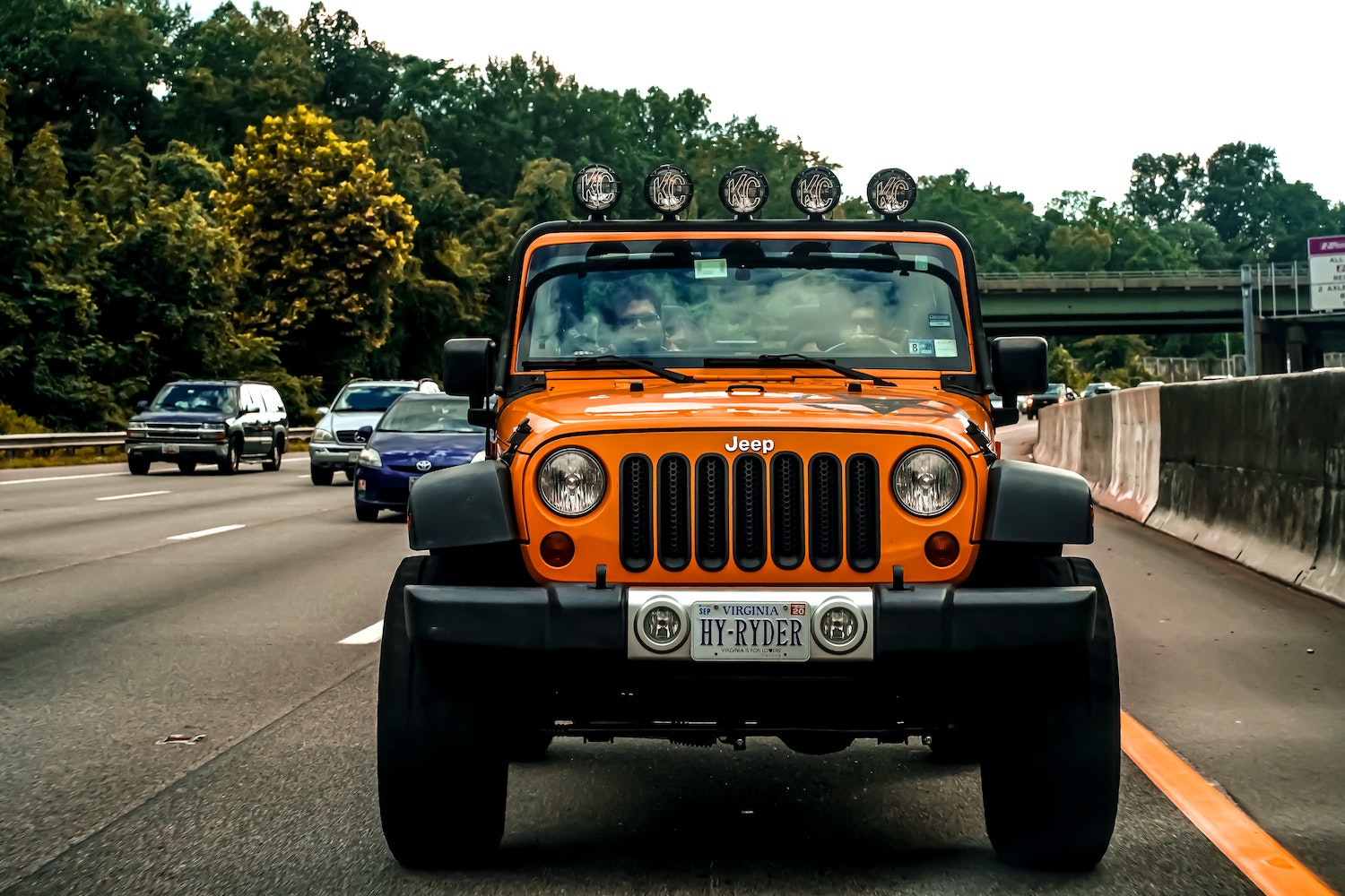 Orange Jeep Wrangler driving down the highway.