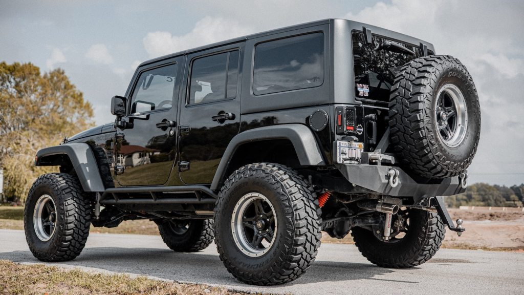 Black picks up a Jeep Wrangler Unlimited parked on the pavement in the country.