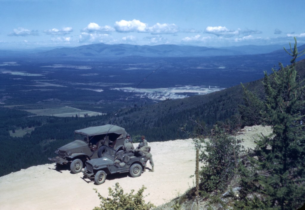 Dodge half-ton "Command car" truck and Jeep Willys parked on a mountain pass during a WWII training exercise.