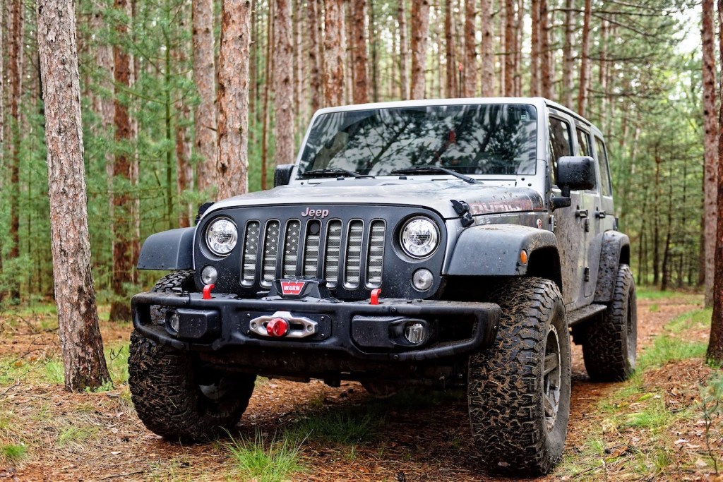 Gray Jeep Wrangler Unlimited parked on a trail in the woods.