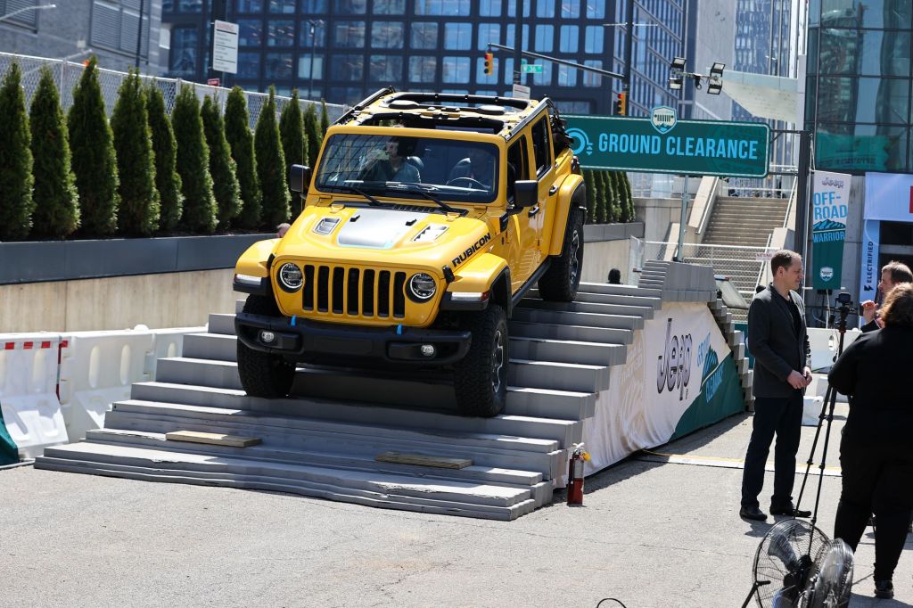 A yellow Jeep Wrangler coming down an incline. 