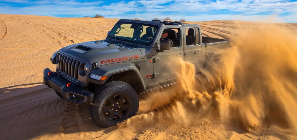 A grey Jeep Gladiator shows off its capability in the sand as a mid-size truck.