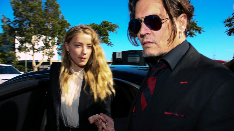 Johnny Depp and Amber Heard getting out of a black sedan in a sunny parking lot.