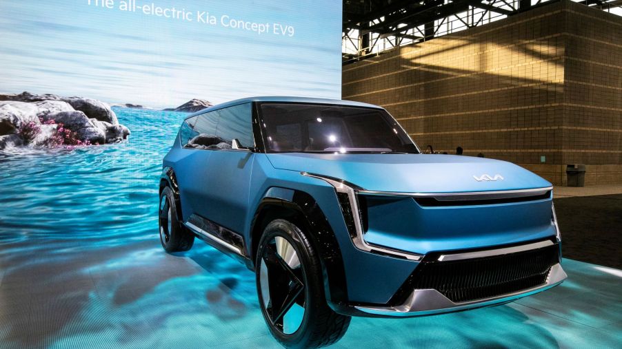 A blue Kia EV9 concept on a blue water simulated background and floor.