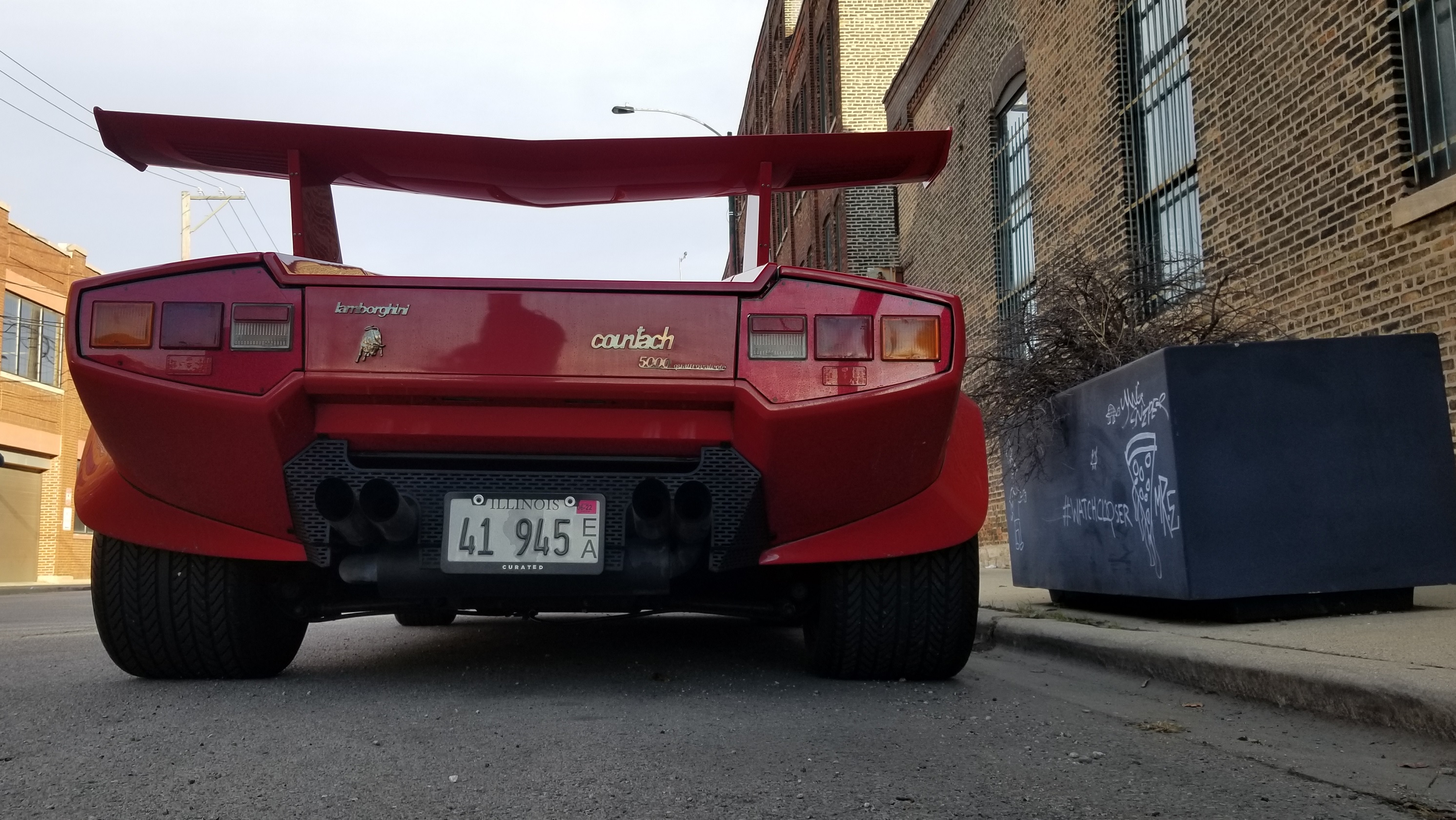 The rear wing view of a red Lamborghini Countach LP5000 QV parked on a Chicago street