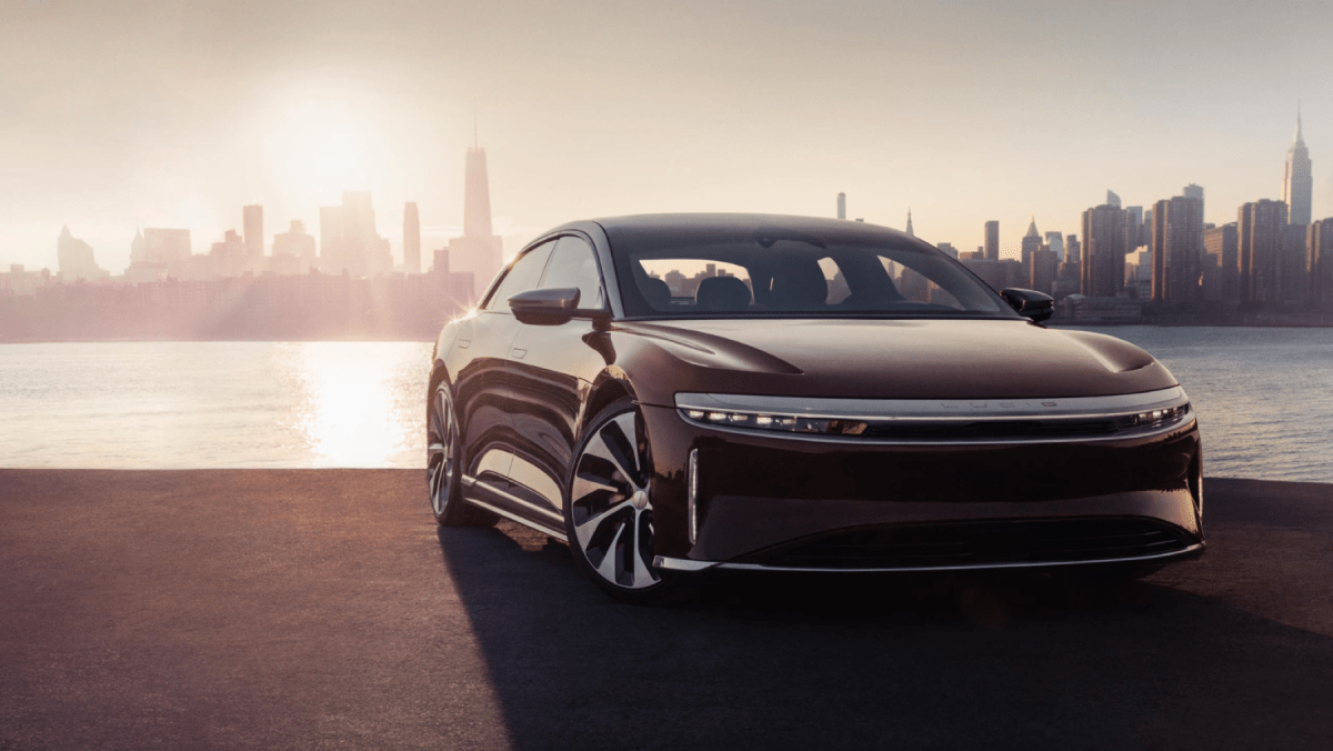 The Lucid Air luxury electric car parked in front of a river, city skyline, and setting sun
