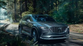 A gray 2022 Mazda CX-9 midsize SUV is driving on the road.