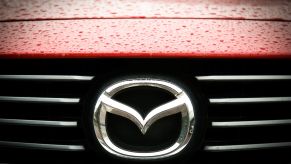 A silver Mazda logo, creator of the Mazda museum, on a red background.