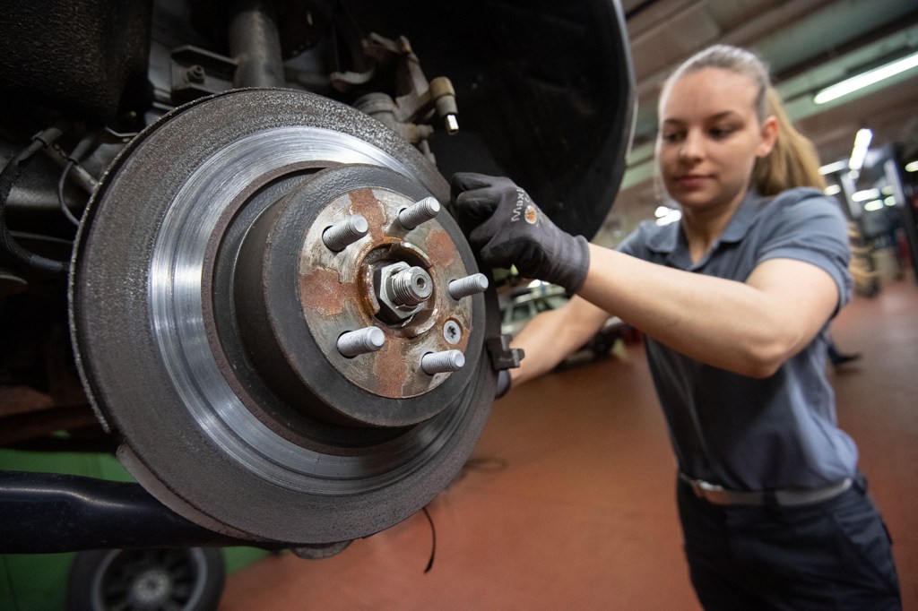 Mechanic working on the brake system of a car, bleeding brakes via caliper bleeder screw