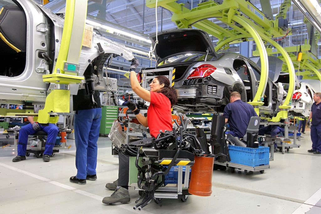 A mercedes employee assembles an S-Class on a factory floor.