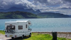 RV travelers parked in front of a body of water with mountains in the background.