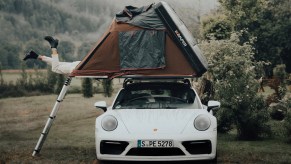White Porsche 992 911 Carrera with roof tent in German black forest