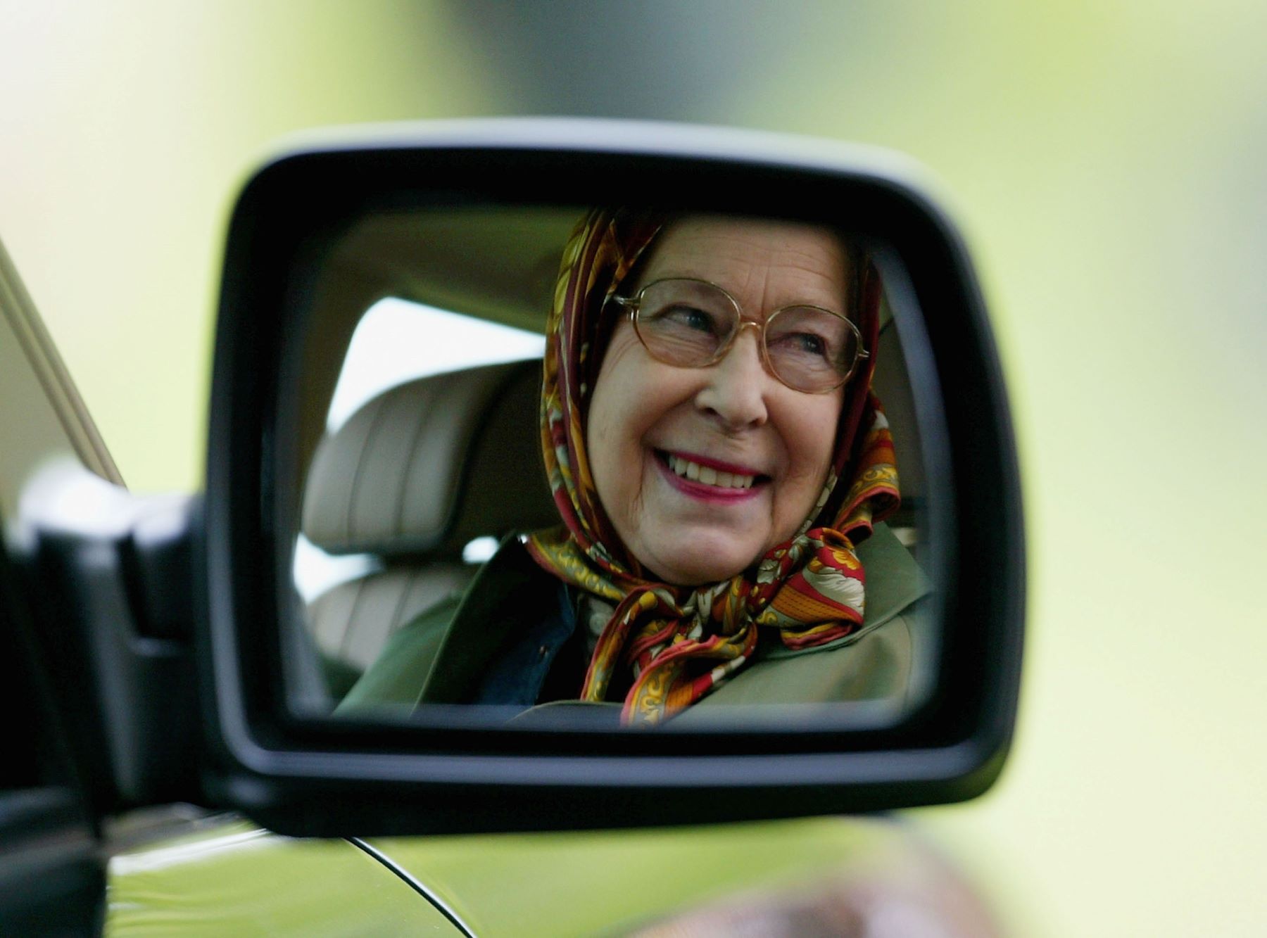 Queen Elizabeth II reflected in a mirror of a Land Rover as she competes in the Driving Grand Prix in Windsor, England