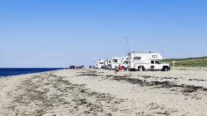 A few RVs camping on a beach.