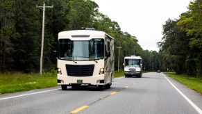 Two RVs driving down a road.