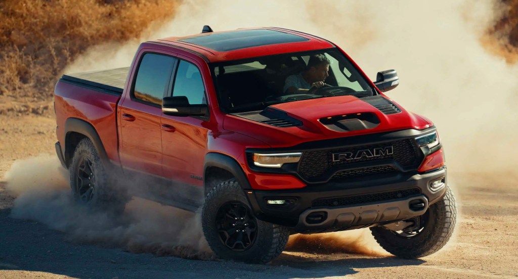 A red 2022 Ram TRX off-road pickup truck is driving in the sand. 