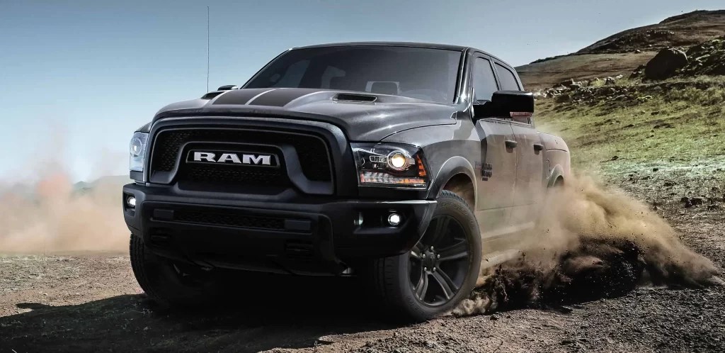 A grey 2022 Ram 1500 Classic shows off its capability as a full-size truck. A hilly terrain is seen behind it.