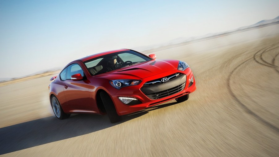 A red 2016 Genesis Coupe drifting on a track