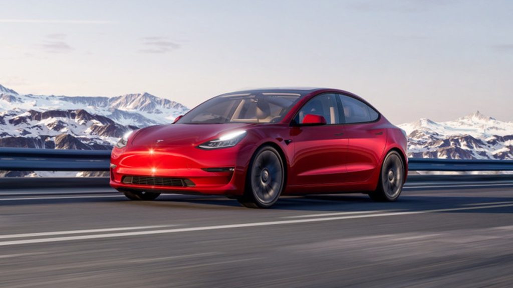 Red 2022 Tesla Model 3, a car that's loved and hated, with mountains in the background
