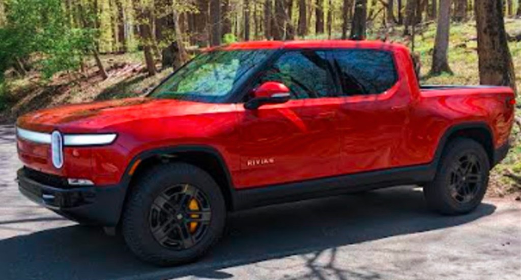 A red 2022 Rivian R1T Launch Edition electric pickup truck is pared on a sunny day.