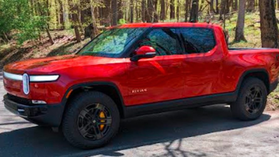 A red 2022 Rivian R1T Launch Edition electric pickup truck is pared on a sunny day.