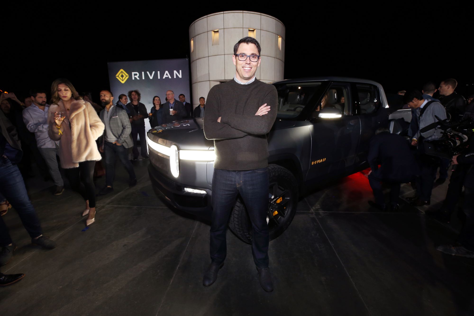 Rivian's CEO, known to have commented on the battery shortage, standing in front of a Rivian pickup truck.
