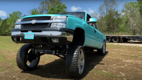 Silverado 1500 pickup truck with a dramatic "Carolina Squat" driving through a field.