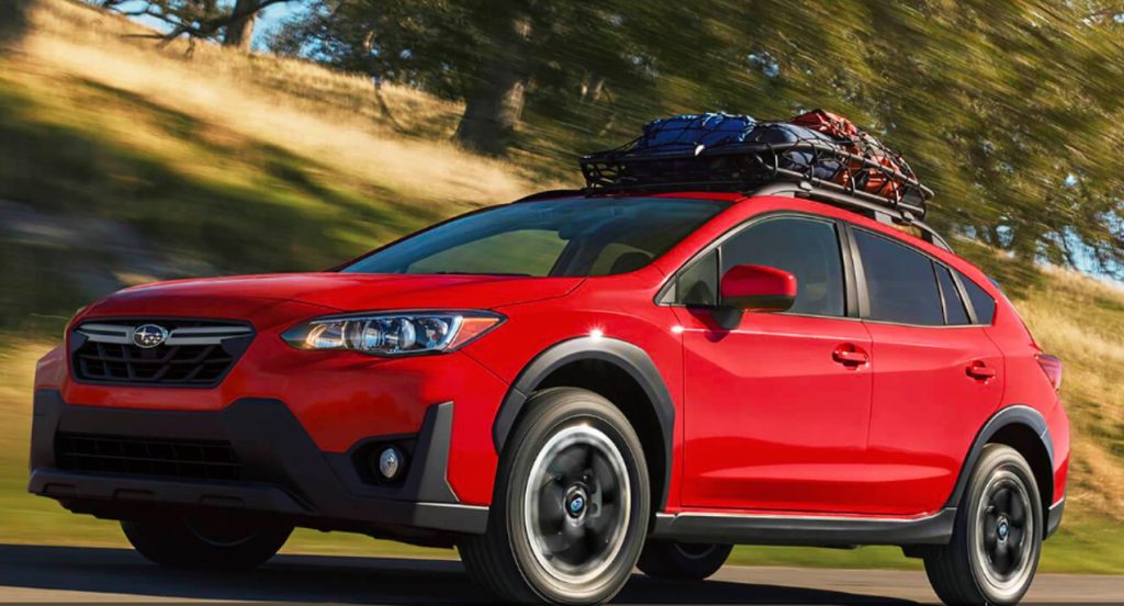 A red 2022 Subaru Crosstrek Premium subcompact SUV is driving on the road. 
