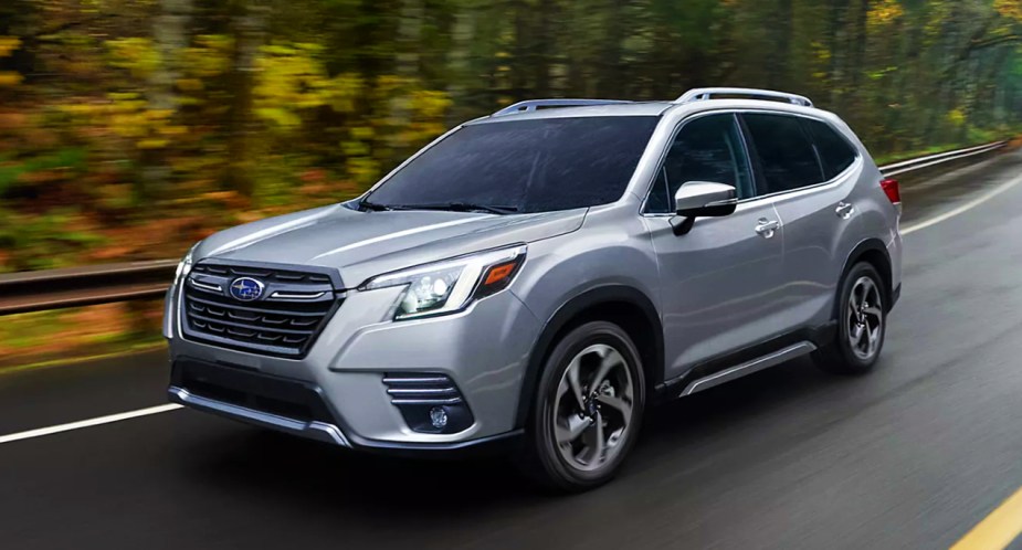 A gray 2022 Subaru Forester small SUV is driving on the road.