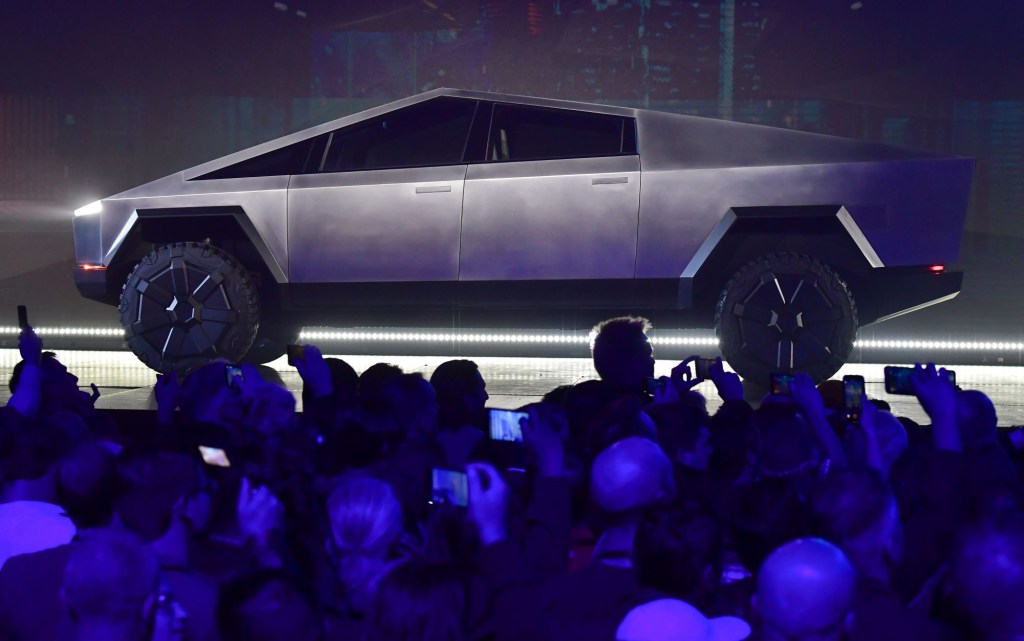 Tesla Cybertruck on a stage in front of a crowd of people with a blue haze.