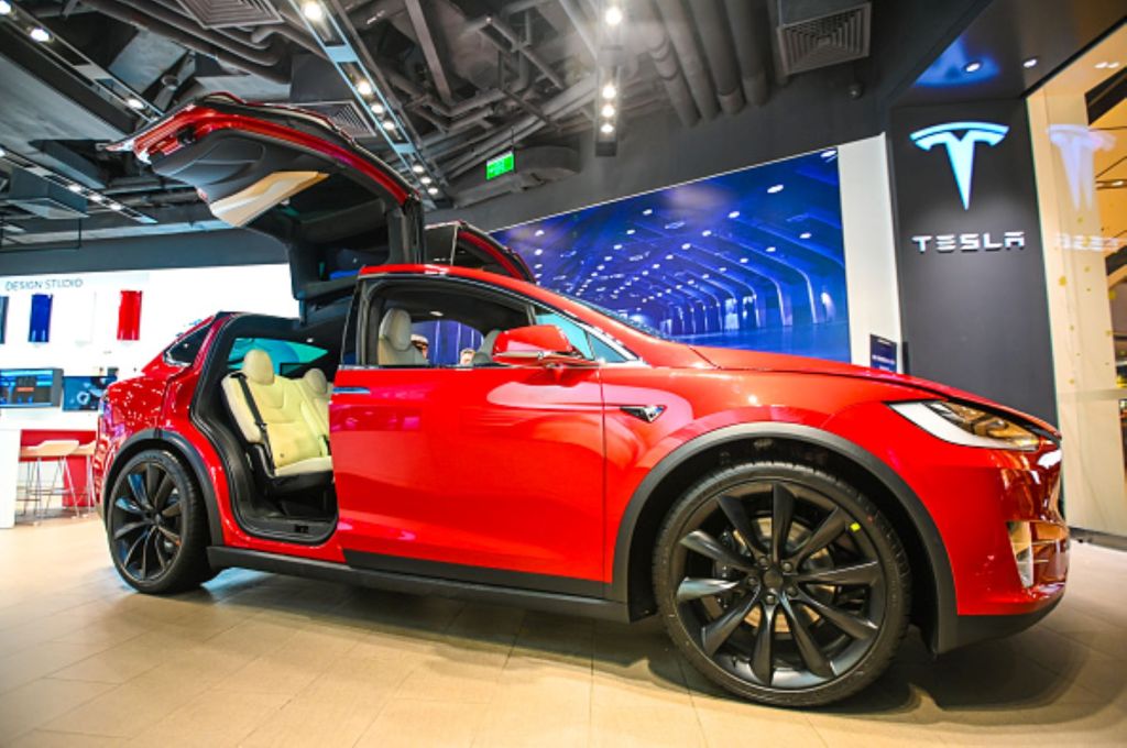 A red Tesla model X with the doors up, on of the most-expensive EV options. 