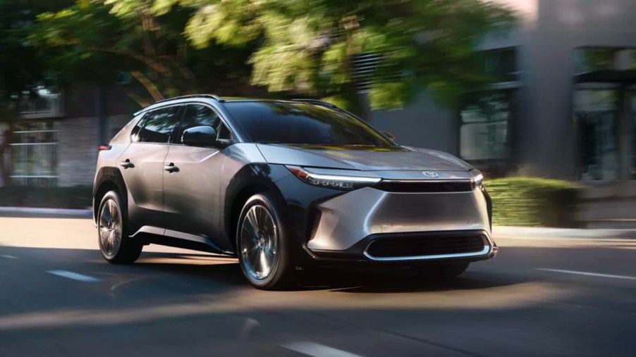 A gray 2023 Toyota bZ4X electric SUV is driving down the road.