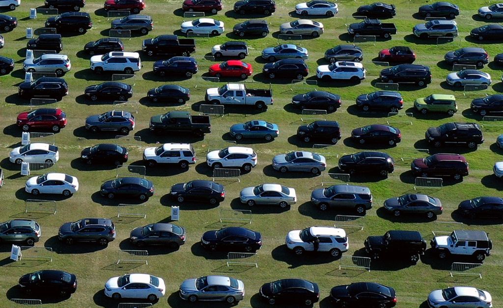 A line of cars, like you would see for sale on Vroom, lined up in a field. 