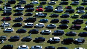 A line of cars, like you would see for sale on Vroom, lined up in a field.