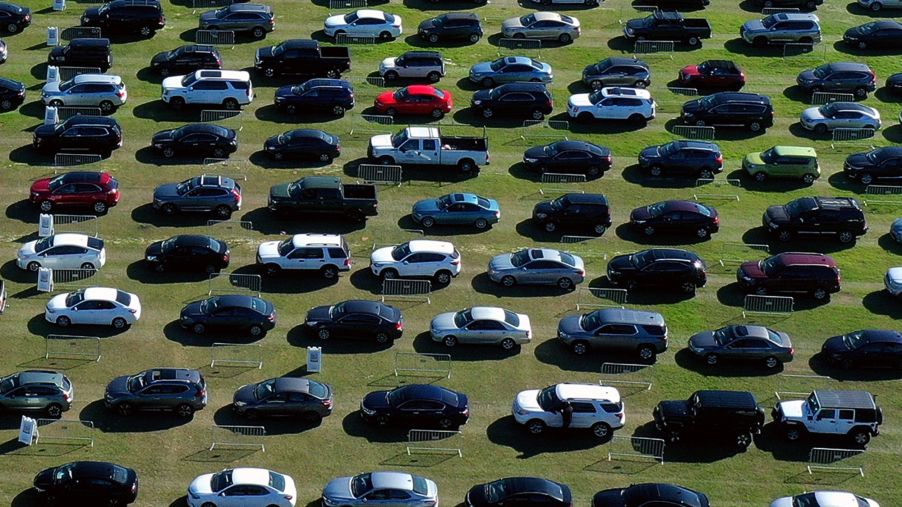 A line of cars, like you would see for sale on Vroom, lined up in a field.