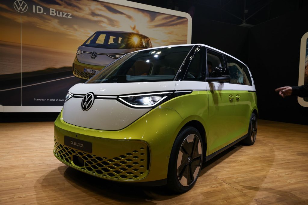 A green and white Volkswagen ID. Buzz inside on light colored wood floors. 
