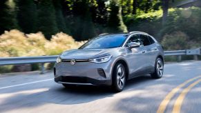 A silver 2022 Volkswagen ID. 4 driving down a wooded area.