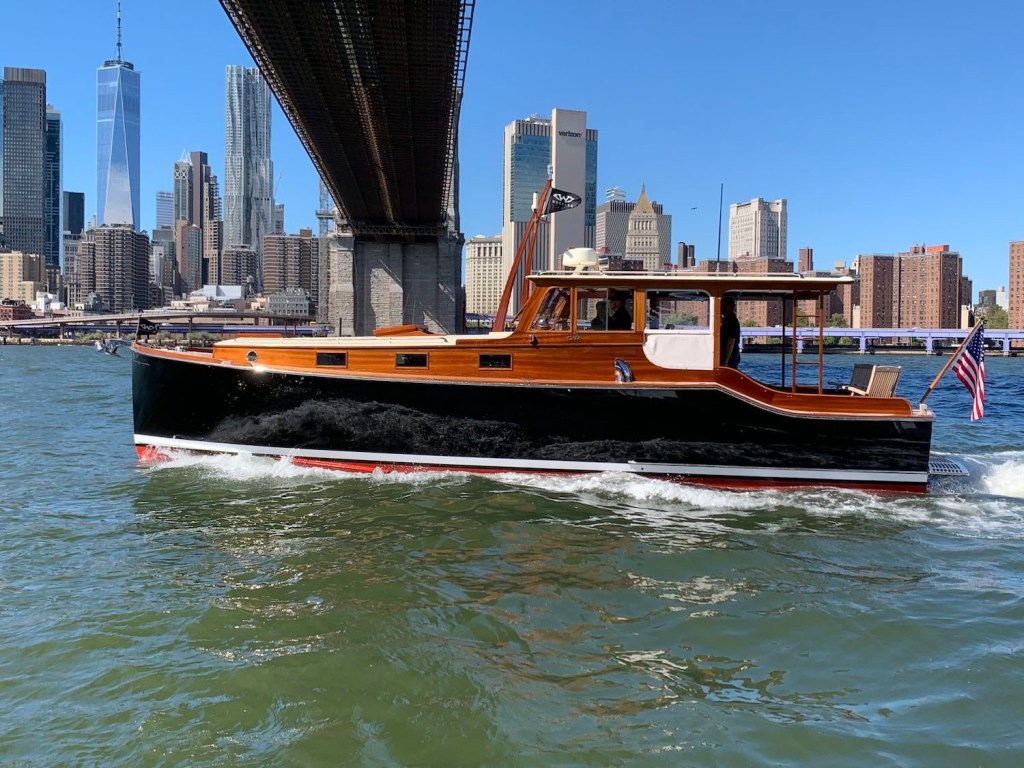The Wheeler 38 restomod sailing through the bay of New York City, the Manhattan skyline in the background.