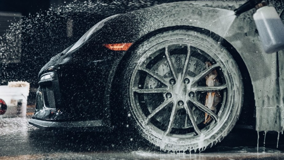 a car wheel covered in thick soap foam, an essential part of cleaning your car for sale