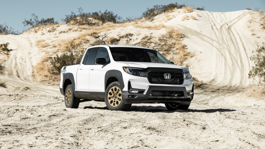 White Honda Ridgeline, a truck that's loved and hated, parked in front of a sand dune