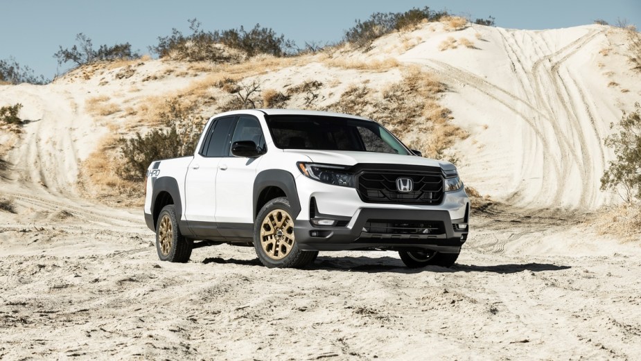 White Honda Ridgeline, a loved and hated truck, parked in front of a sand dune