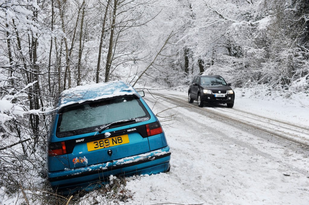 Abandoned car by side of road in snowy weather, UK.