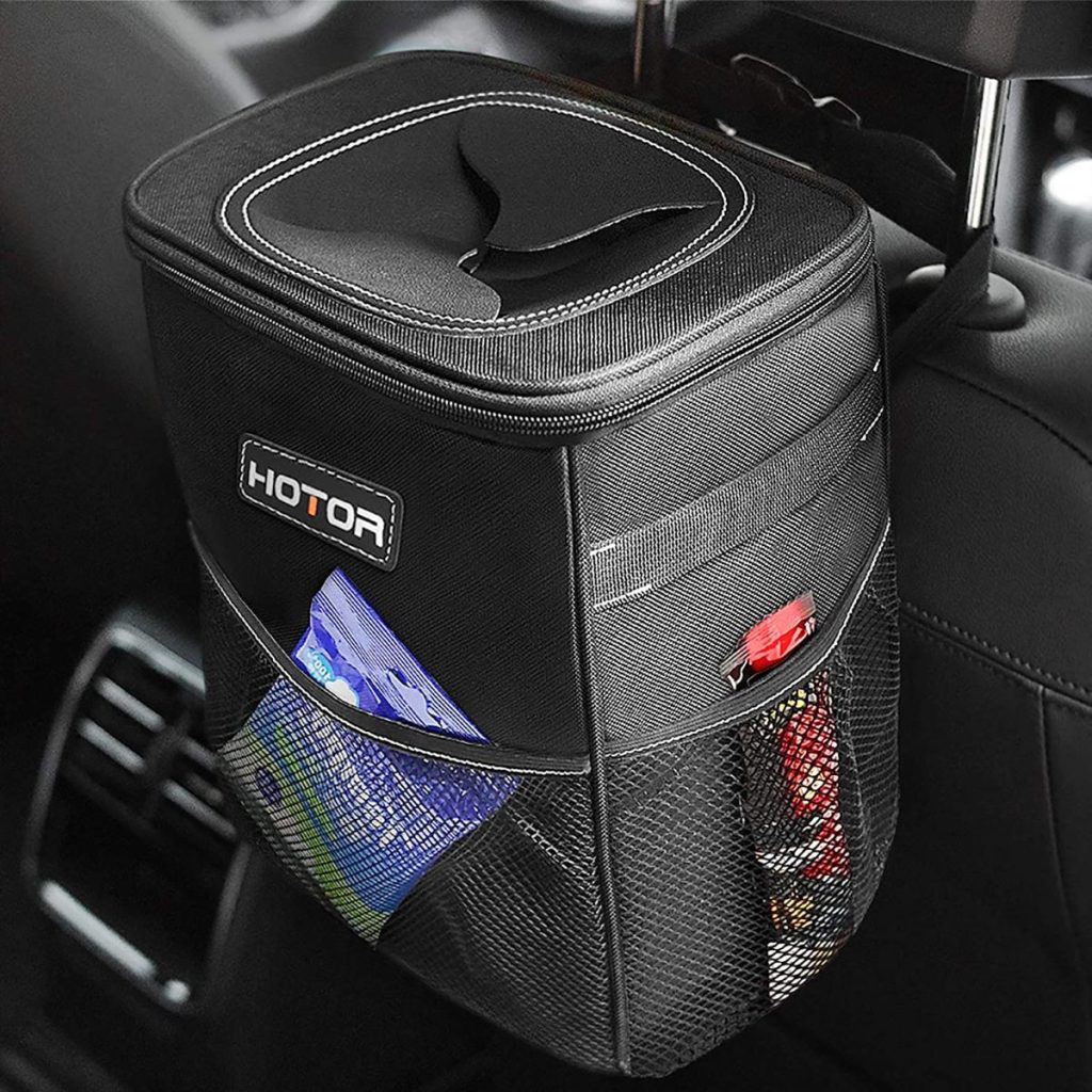 Black car trash can attached to the back of a car seat. A trash car is a must-have car accessory